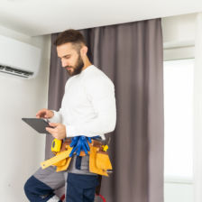 Male HVAC tech using tablet to diagnosis a ductless AC unit