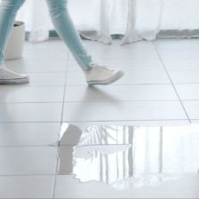 A woman and a man walking past a puddle of water on the floor