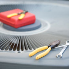 Closeup of an outdoor ac unit top with tools sitting on top