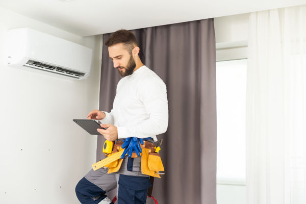 Male HVAC tech using tablet to diagnosis a ductless AC unit