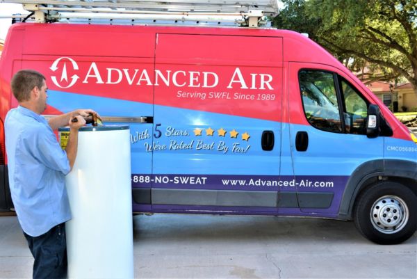Advanced Air tech with a tank water heater next to a service van
