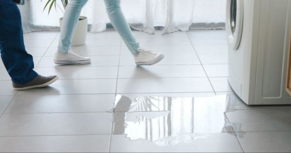 A woman and a man walking past a puddle of water on the floor