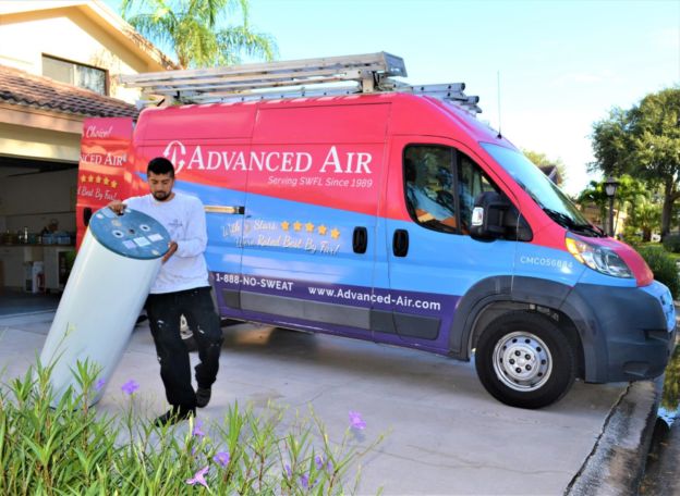 Tech walking a tank water heater from his service van to a house