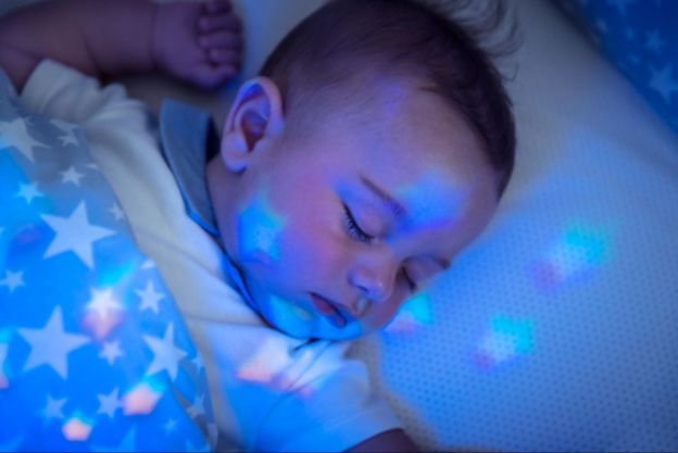Baby sleeping with a starry blanket and nightlight