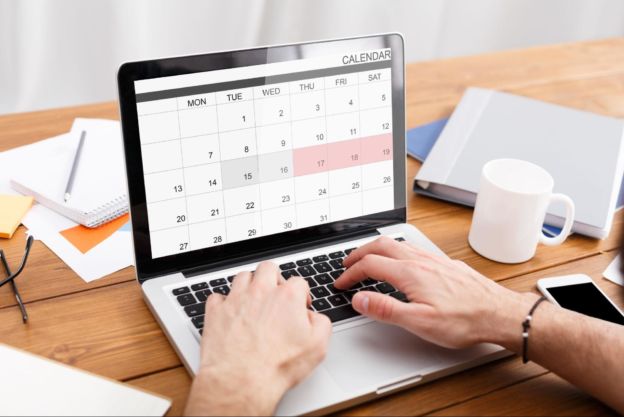 Person typing on a laptop showing an open calendar. 