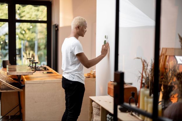 Person adjusting his smart thermostat in his kitchen